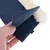 Gros plan sur une main tenant un accessoire en tissu bleu avec intérieur doux et bordure imitation fourrure blanche, étiquette noire marquée 'L' visible.