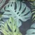 Primer plano de un diseño de hojas tropicales en tonos verdes y azules sobre tela.