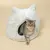 Grijze kat zit in een wit, pluizig kattenhuis met oordesign en ronde ingang.