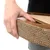 Hand holding a product made of corrugated cardboard with a wood look. Close-up of material texture and handle opening.