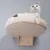 Plateforme murale en bois clair avec coussin beige, un chat blanc et gris allongé dessus. Support mural visible sous la plateforme.