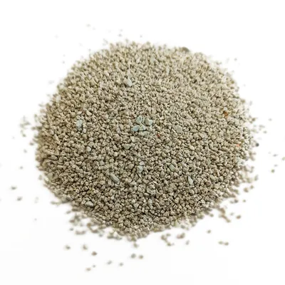 Litière minérale pour chat, granulés fins de couleur beige et gris clair visibles en tas sur fond blanc.