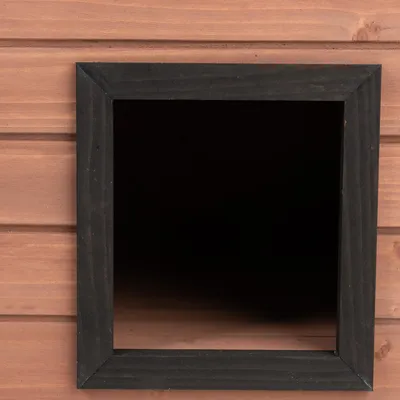 Nahaufnahme eines quadratischen schwarzen Eingangsrahmens aus Holz, eingebettet in eine braune Holzstruktur.
