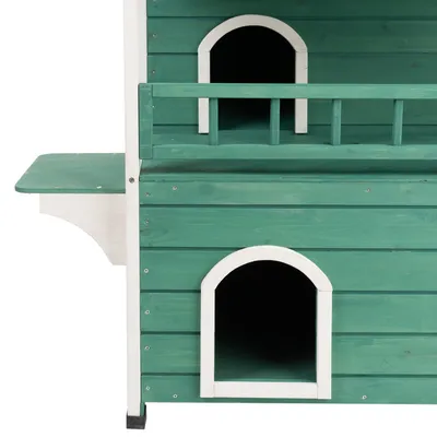Grünes Holzhaus mit zwei Eingängen, Balkon und seitlicher Plattform. Geeignet für Haustiere oder als dekoratives Element.