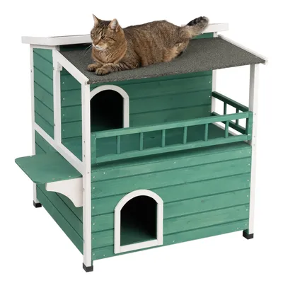 Grünes zweistöckiges Katzenhaus aus Holz mit Balkon und Dachterrasse, darauf eine braune Katze liegend.