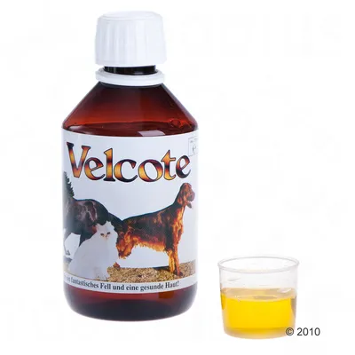 Fles Velcote met afbeelding van hond en kat op het etiket, naast een maatbekertje met gele vloeistof. Tekst op etiket deels in het Duits: 'für ein fantastisches Fell und eine gesunde Haut!'.