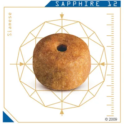 Гранула за котки с надпис SAPPHIRE 12 и Siamese, показана върху измервателна схема за размер. Видим е един кръгъл гранул с дупка в средата.