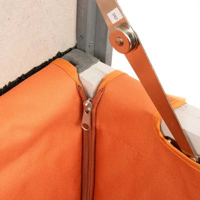 Nahaufnahme eines orangefarbenen Stoffbezugs mit Reissverschluss, befestigt an einer Holz- und Metallkonstruktion.