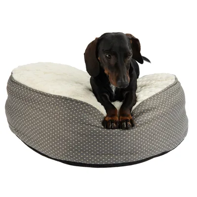 Hund på en grå, prikket kæledyrsseng med hvid plyssoverflade.