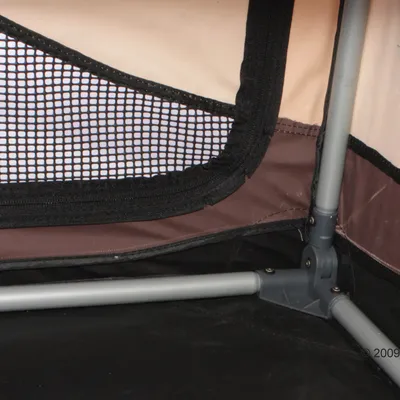 Close-up of a mesh window and sturdy metal frame corner inside a pet carrier or crate, showing ventilation and construction details.