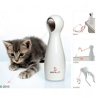 Laserová hračka pre mačky FroliCat BOLT, biela, s červeným laserom. Zobrazené možnosti použitia: na stole, na podlahe a v ruke. Mačiatko sleduje laserový bod.