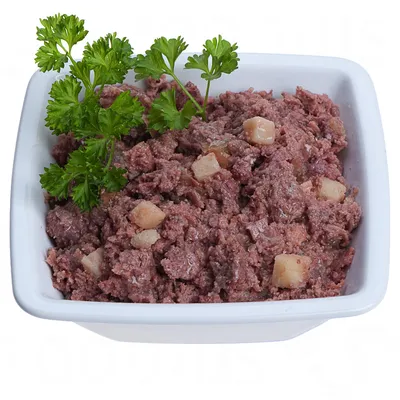 Posuda s vlažnom hranom za životinje, sastoji se od komadića mesa i kockica krumpira, ukrašena svježim peršinom.