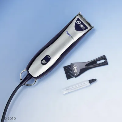 Oster PowerMax klippemaskine med on/off-knap, sort børste med Oster-tekst og lille tube olie. Alle dele synlige på lys baggrund.