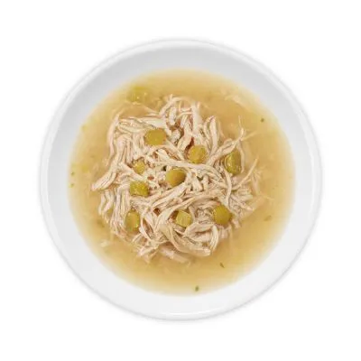 Wit bord met natvoer bestaande uit stukjes vlees in bouillon met enkele groene groentestukjes, geschikt als huisdiervoeding. Merk- of productnaam niet zichtbaar.