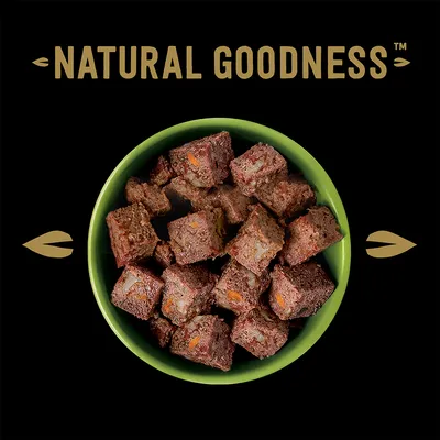 Natural Goodness. Кубики из натурального мяса и овощей в зеленой миске на черном фоне.