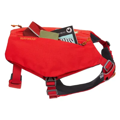 Ruffwear röd hundsele med ficka, fylld med snacks och tillbehör. Justerbara remmar och robusta spännen synliga.