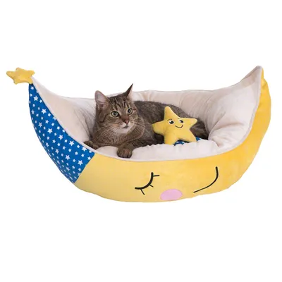 Cama para gatos en forma de luna amarilla con detalles azules y blancos, incluye un cojín de estrella sonriente. Gato atigrado tumbado dentro de la cama.