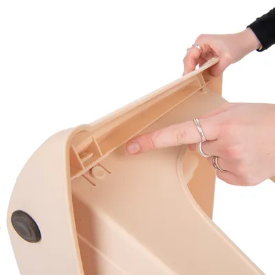 Detailaufnahme einer Hand, die auf den Verschlussmechanismus eines beige-farbenen Kunststoffbehälters zeigt.