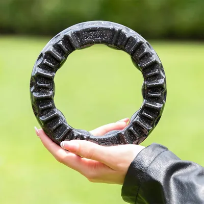 Anneau noir en plastique à reliefs, tenu dans une main, fond extérieur flou. Aucun texte ou marque visible.