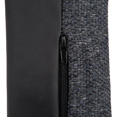Close-up view of a zip between black faux leather and grey textile fabric.