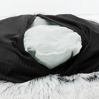 Nahaufnahme eines geöffneten Tierkissens mit schwarzem Bezug, sichtbarer Netzfüllung und Reissverschluss.