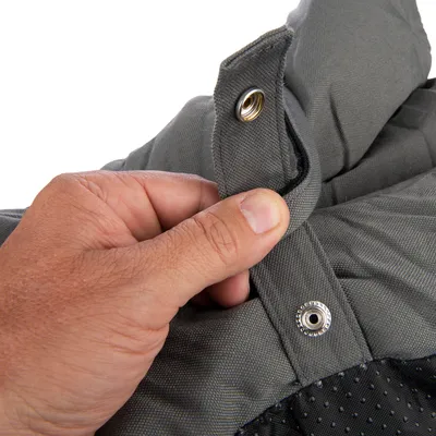 Close-up of a press stud fastening on grey fabric, held by a hand.