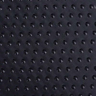 Detalle de superficie de tela negra con puntos antideslizantes en relieve, material sintético visible en primer plano.