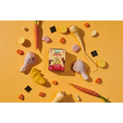Product image showing a grain free chicken pet food pack surrounded by visible ingredients including carrots, parsnips, potatoes, seaweed, and raw chicken pieces.