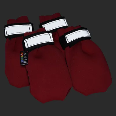 Vier rote Pfotenschuhe mit Klettverschluss und weißem Streifen, Markenetikett 'rukka' sichtbar.