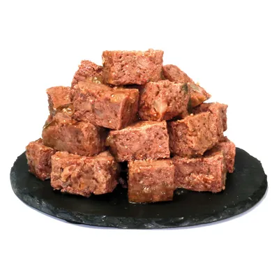 Ułożone kostki mięsa na czarnym talerzu, widocznie soczyste i o naturalnej teksturze.