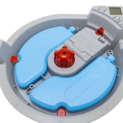 Lemmikkien automaattisen ruokinta-astian sisäosa: kaksi sinistä osaa, punainen lukitusnuppi ja paristokotelo, jossa englanninkielinen ohjeteksti. Näytöllinen ohjauspaneeli ylhäällä.