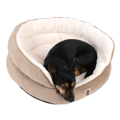 Hund liegt in einem beigen, gepolsterten Haustierbett mit weissem Innenfutter und Markenlogo auf der Vorderseite.