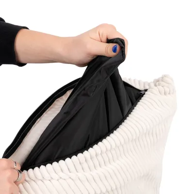 Hand öffnet Reissverschluss eines weissen, gerippten Bezugs und zeigt eine schwarze, wasserabweisende Innenhülle.