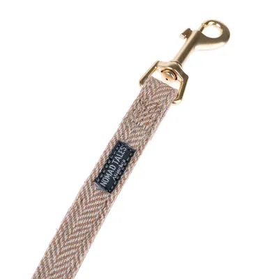 Nomad Tales dog lead with gold-coloured carabiner and beige-white herringbone pattern.