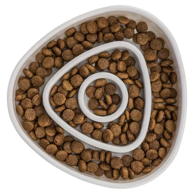 Triangular anti-gulping bowl with spiral-shaped indentations, filled with brown dry food pieces.
