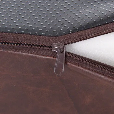 Zbliżenie na brązowy pokrowiec z ekoskóry z zamkiem błyskawicznym, widoczna pianka w środku i szara powierzchnia antypoślizgowa z wypustkami.