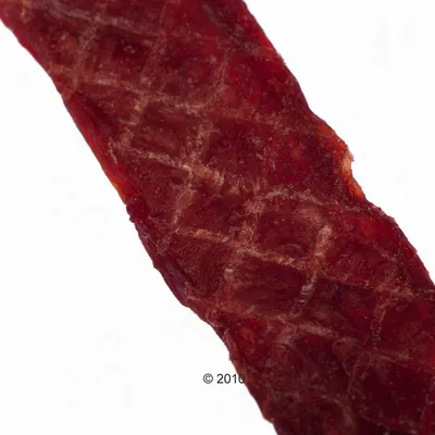 Primer plano de una tira de carne roja y seca con superficie texturizada. © 2010.