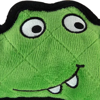 Grønt stoflegetøj med broderet ansigt, store øjne og sorte kanter.