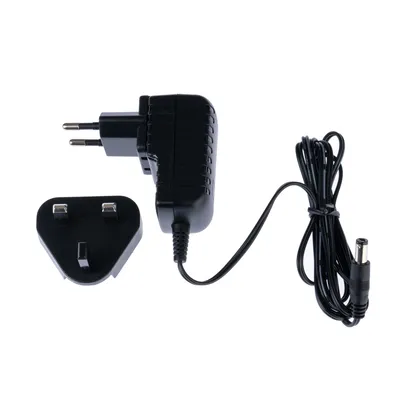 Black power supply with EU and UK plug adapters and cable with DC connector. Suitable for electronic devices.