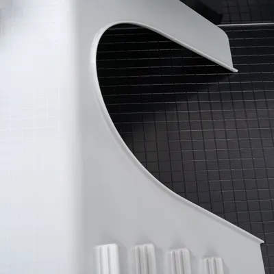 Detailaufnahme einer weissen Kunststoffoberfläche mit gerillten Strukturen und schwarzem Hintergrund mit quadratischem Muster.