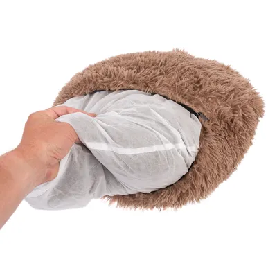 Hand zeigt herausnehmbares Innenkissen mit Netzbezug aus einem braunen, flauschigen Haustierbett.