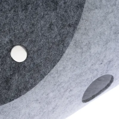 Gros plan sur une surface en feutre gris avec un bouton métallique et un trou rond visibles. Matériau : feutre, détail de fixation.