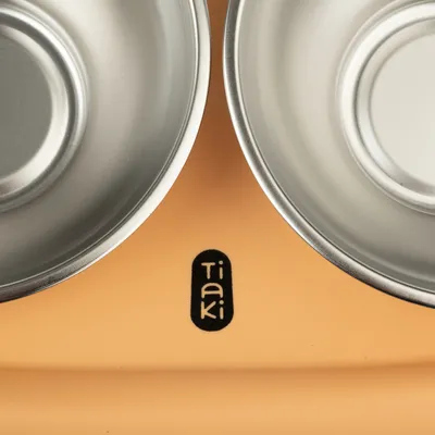 Tiaki double metal bowl on orange base, suitable for food or water.