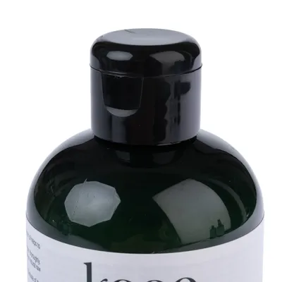 Schwarzer Klappverschluss einer dunkelgrünen Flasche mit teilweise sichtbarem Schriftzug 'kooa'.