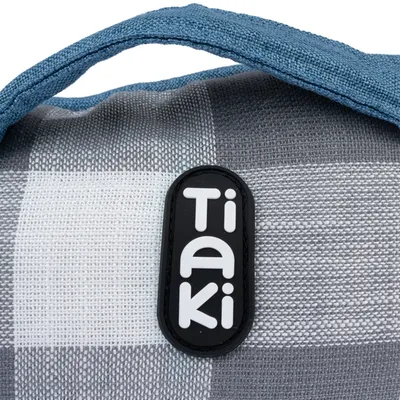 Tiaki-logotyp på ett gråvitt rutigt tyg med blått handtag.