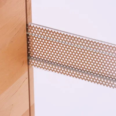 Dettaglio di una striscia di metallo perforata fissata tra due pannelli di legno.