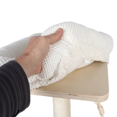 Hand hebt eine weisse, strukturierte Polsterauflage von einer Holzplattform mit Sisalstange. Zeigt abnehmbare und waschbare Auflage.