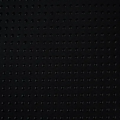 Surface en tissu noir avec picots antidérapants disposés en grille régulière, détail du matériau visible.