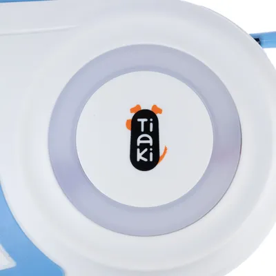 Tiaki inscrit au centre d’un objet rond blanc avec détails gris et bleu, logo noir et orange visible.