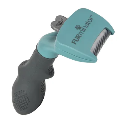 Brosse avec manche ergonomique en plastique et tête métallique, marque Furminator, texte visible : FURminator et FURejector sur le bouton gris.